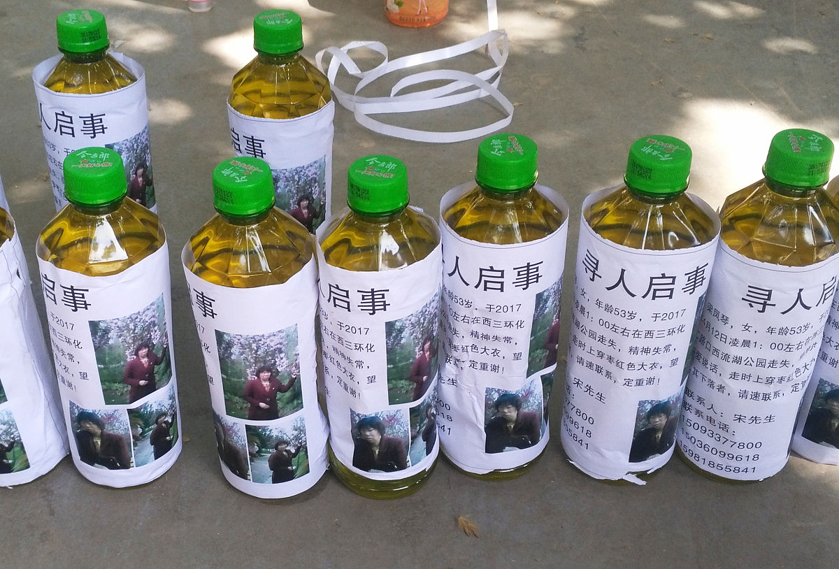 2017年4月23日,郑州,一名男子把带有母亲照片的寻人启事粘贴在饮料瓶