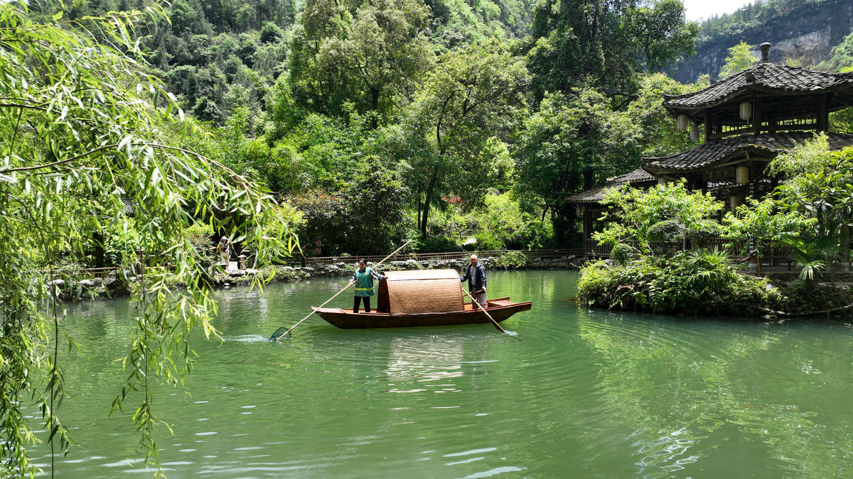 在幽深的峡谷中两岸树木茂盛碧绿的湖水上飘荡着淡淡的雾气偶尔有一叶轻舟在游荡岸边一间茅草屋旁坐着一个弹琴的美女琴声悦耳动听。根据描述作一首七言绝句要求押韵。