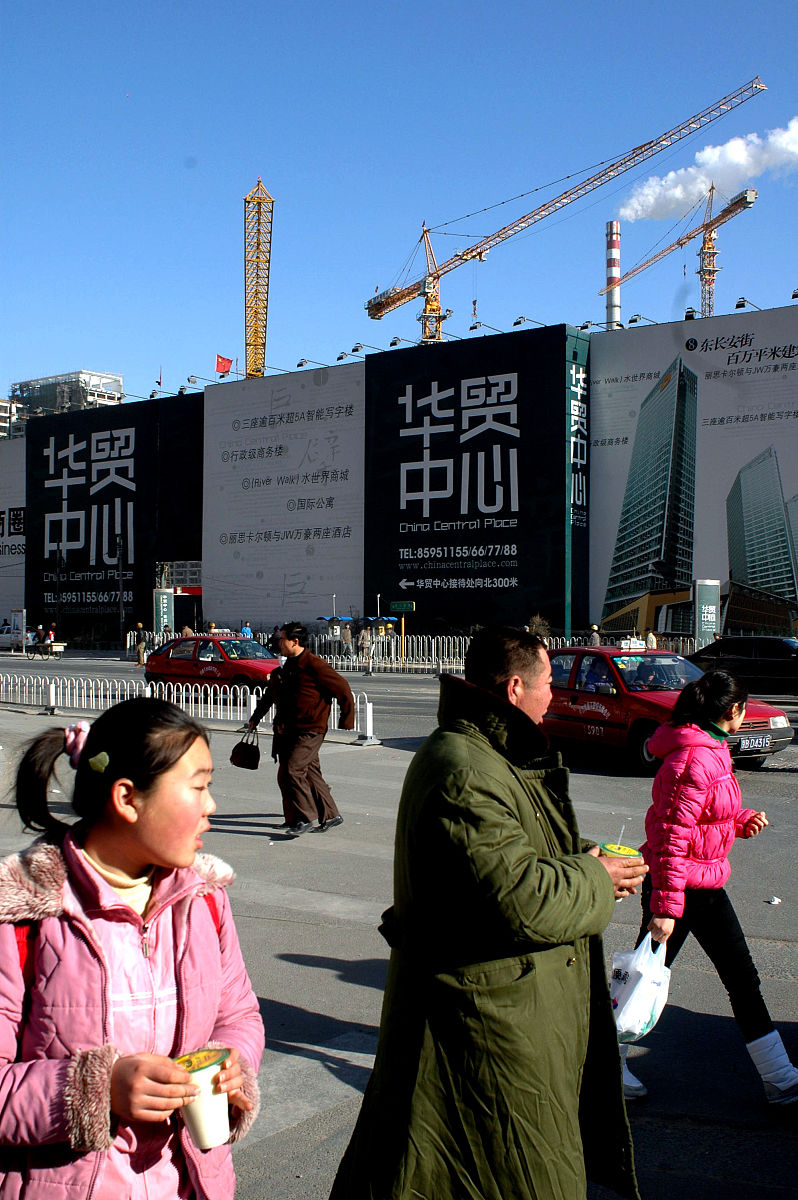 2005年1月3日,北京cbd大望路,手拿豆浆的市民过马路,远处是房地产的广