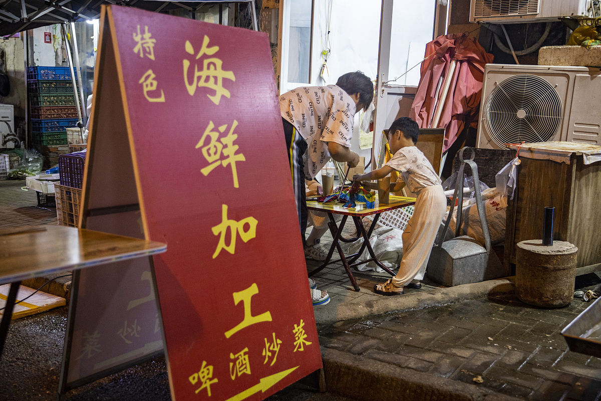 2021年7月2日,青岛,啤酒炒菜,海鲜加工的牌子很醒目.