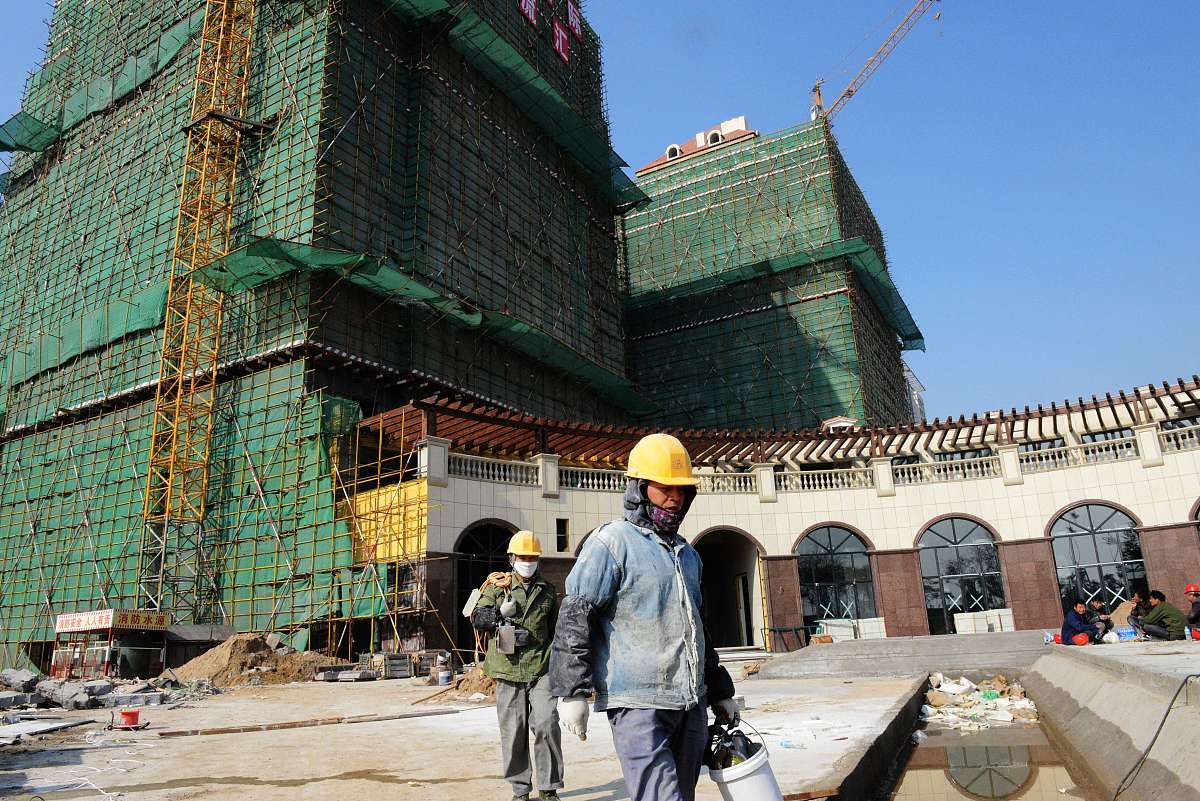 2012年11月17日,山东青岛2位建筑工人从一在建楼盘前走过.
