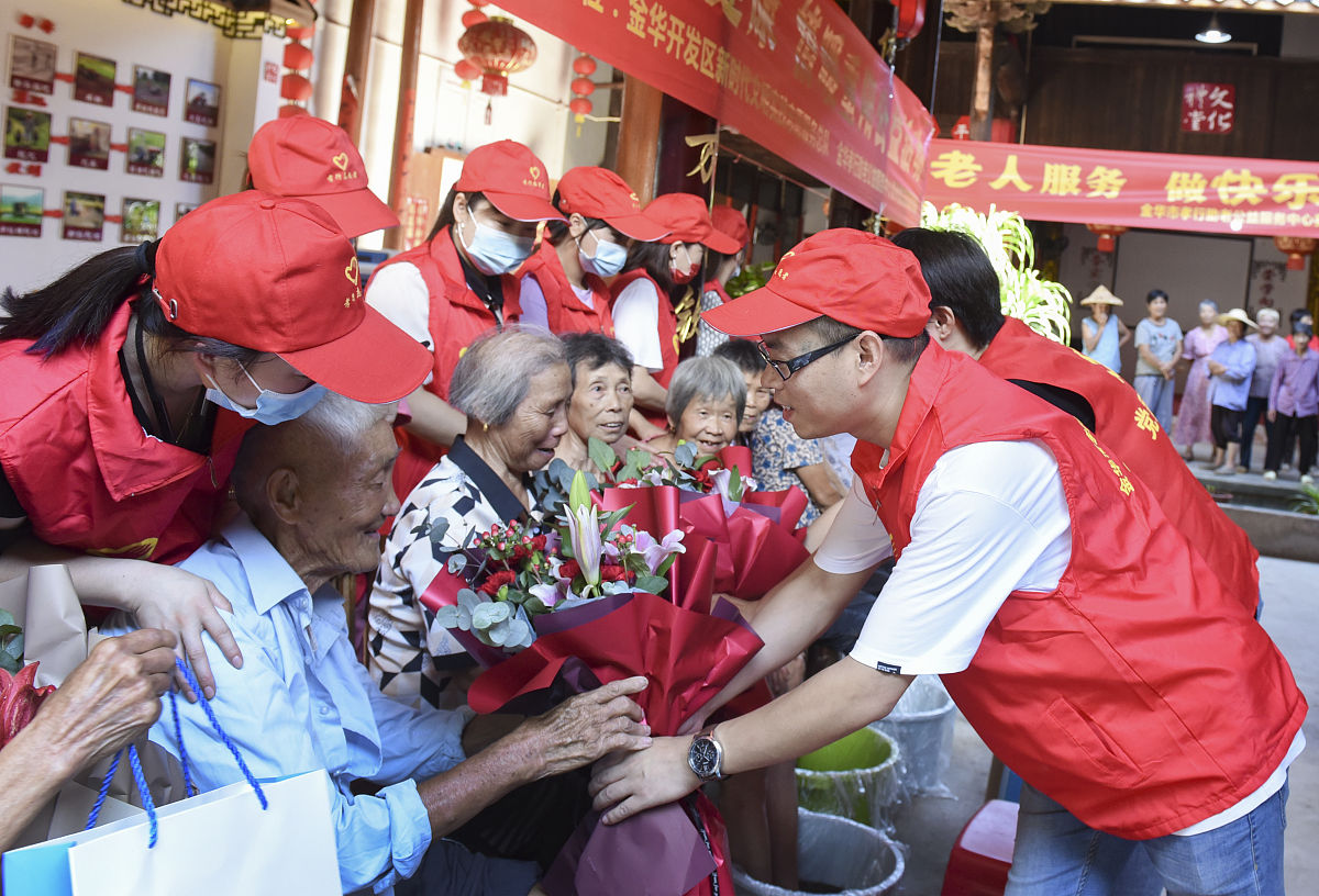 2021年10月9日,浙江金华,重阳节之际,志愿者给老年人送上鲜花.