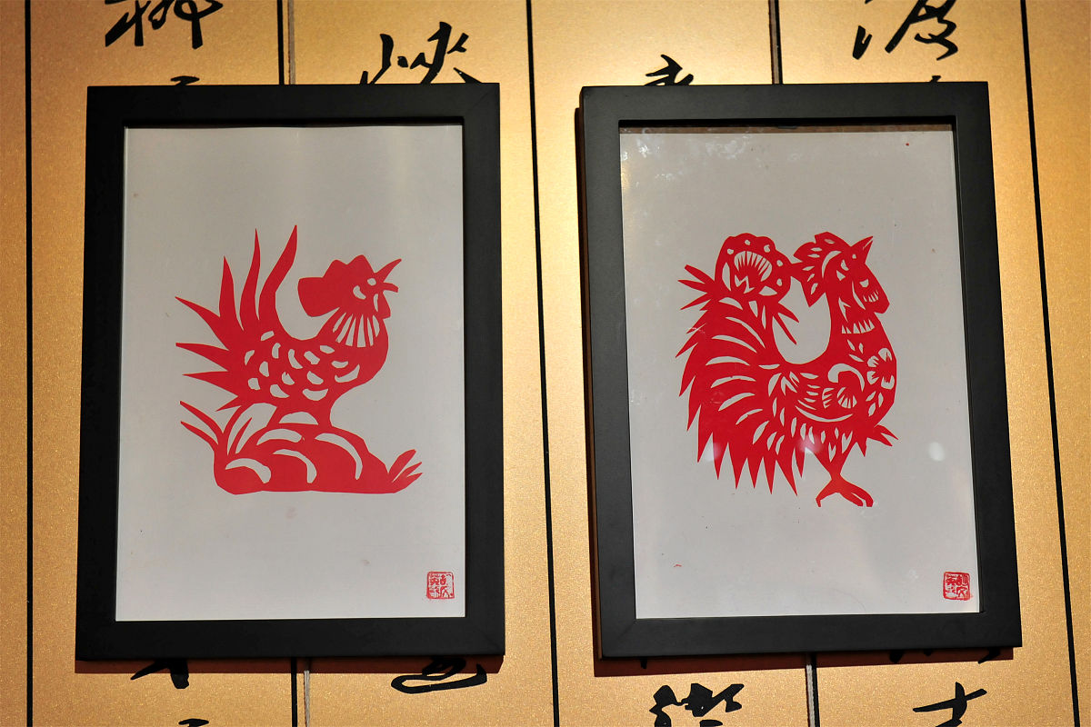 从纹饰和技法上重点展开赏析：张吉根的《百鸟朝凤》是一件阴刻剪纸作品采用了水平式的二方连续规律。作品中的纹饰主要有云纹、月牙纹、双线纹等这些纹饰的组合形成了各种不同的图案如花鸟、山水等。其中最为突出的是作品中的鸟它们栩栩如生羽毛的细节处理非常精细形态逼真。此外作品中的色彩运用也非常丰富运用了不同的颜色来突出不同的部分营造出独特的视觉效果。总的来说张吉根的《百鸟朝凤》展现了剪纸艺术的精湛技巧和丰富的创