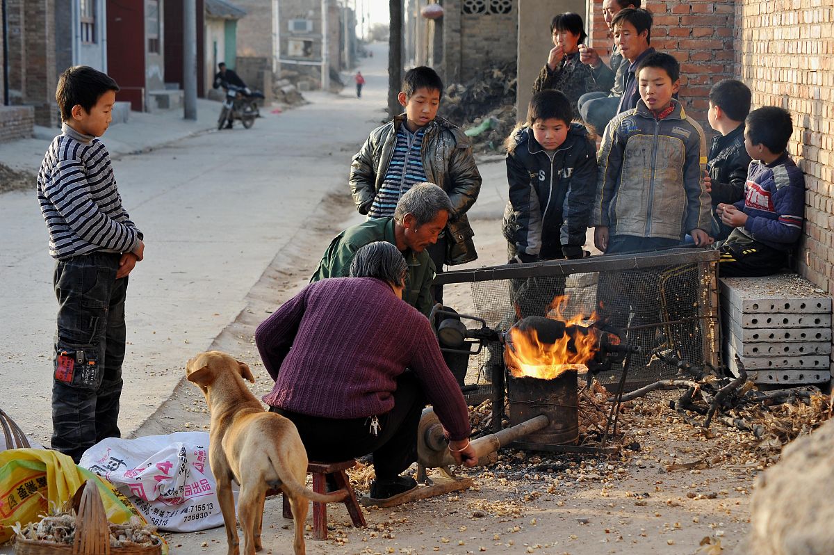 2010年12月11日,山西运城,一位手艺人正在用传统方法为乡亲爆玉米花,