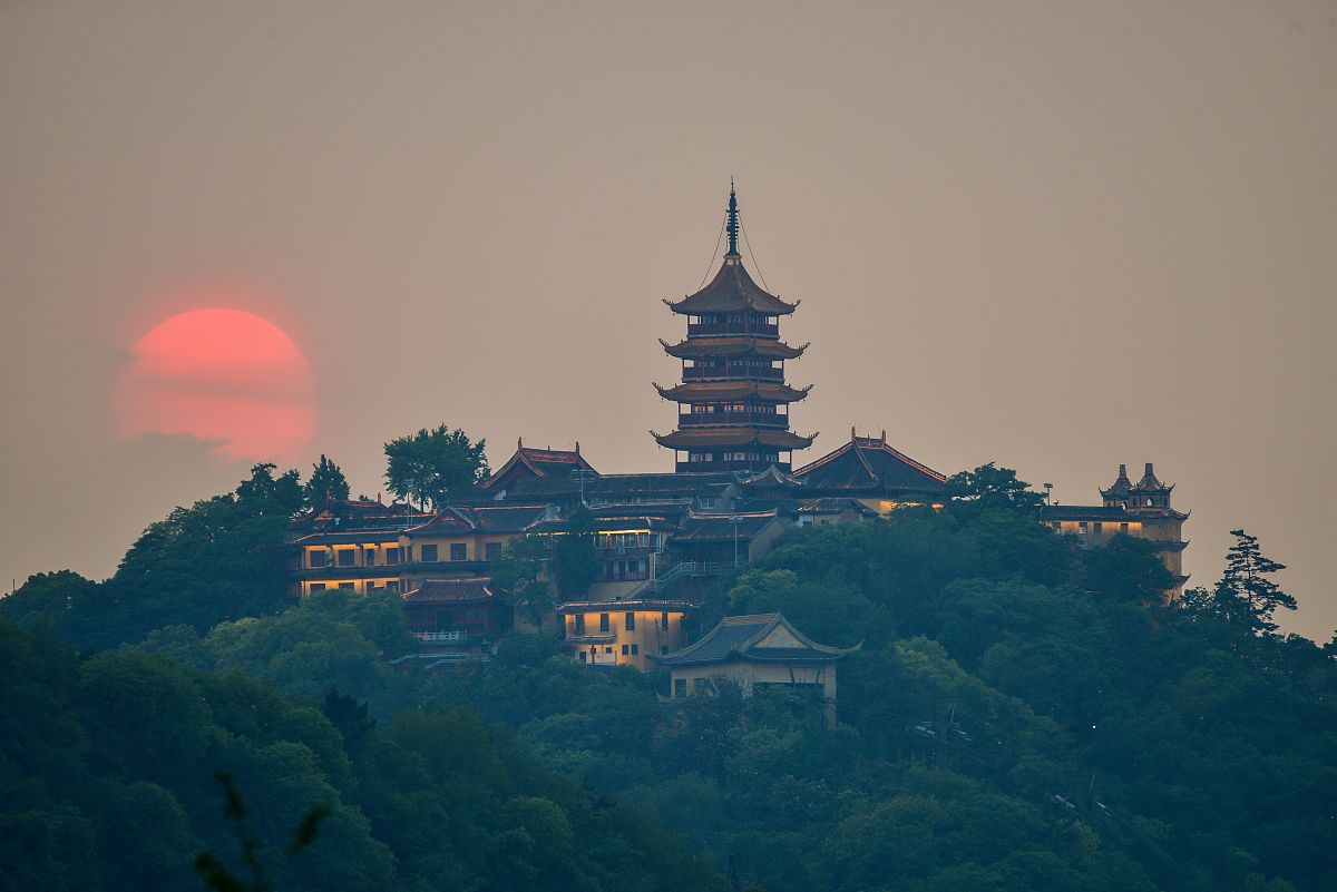 2020年5月11日,江苏南通狼山国家森林公园,夕阳从狼山支云塔旁落下.