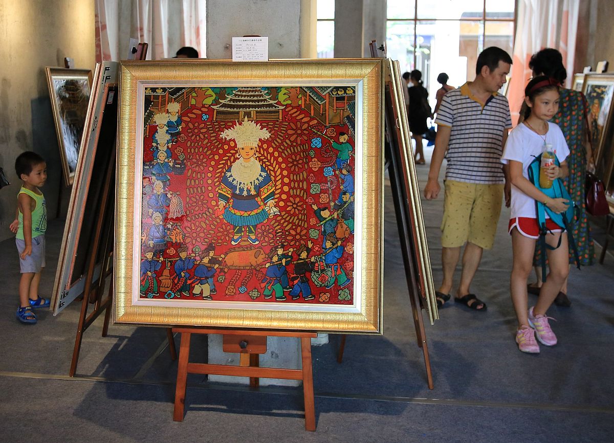 2017年10月1日,在广西柳州市窑埠古镇,游人在观看三江侗族农民漆画展.