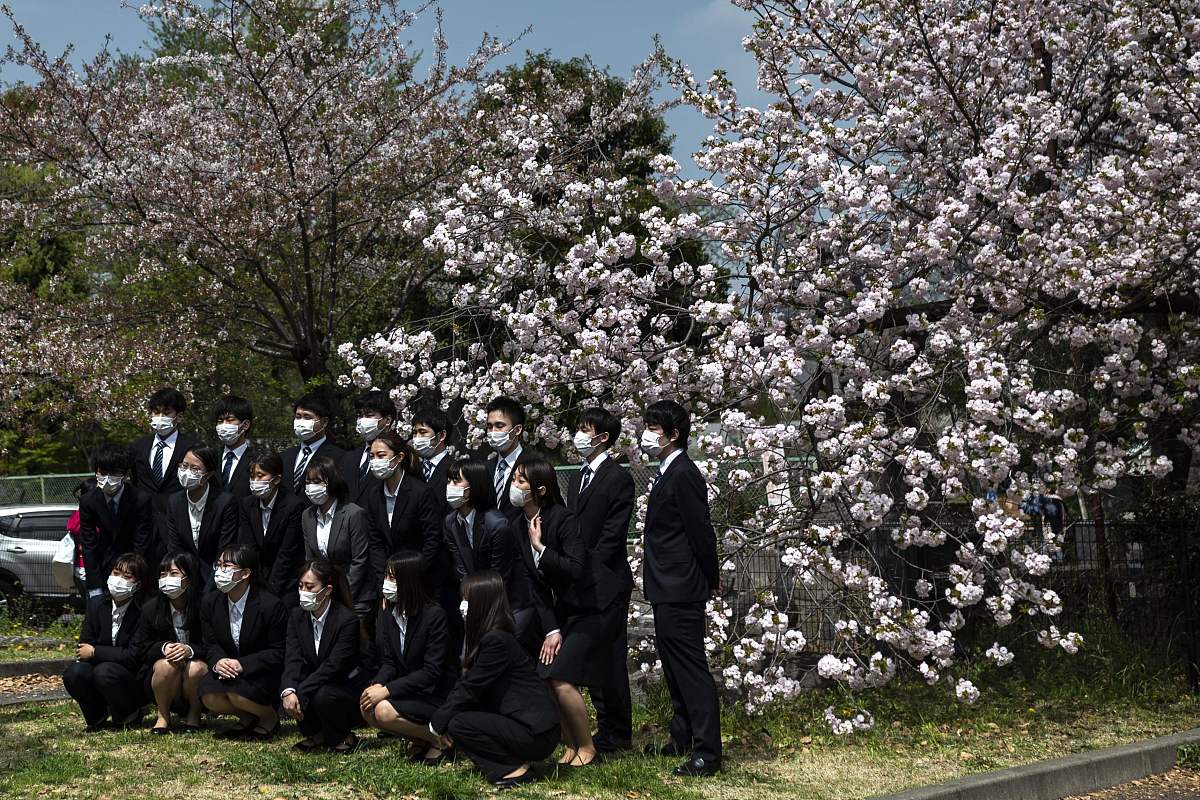 当地时间2021年4月1日,日本东京,新入职员工在樱花树下拍照.世界卫生