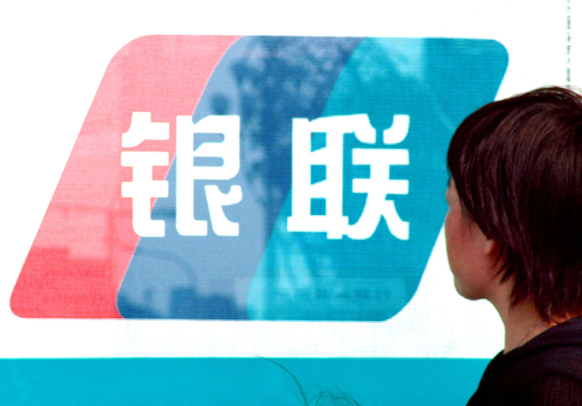 2004年9月23日,行人走过郑州街头银行卡之银联卡的大幅标识前.