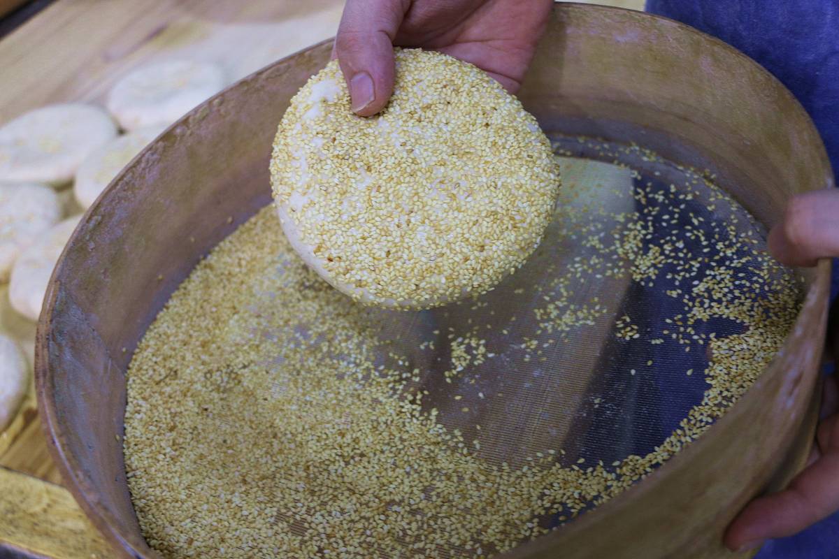 2019年5月6日,河北承德,面食艺人为刚刚制作好烧饼饼坯"穿上"芝麻外衣