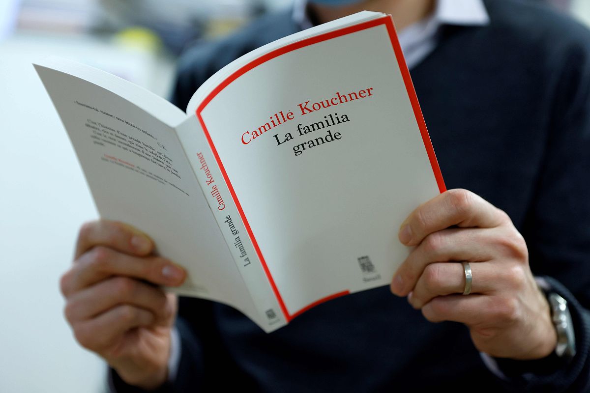 a man reads camille kouchner's book "la familia