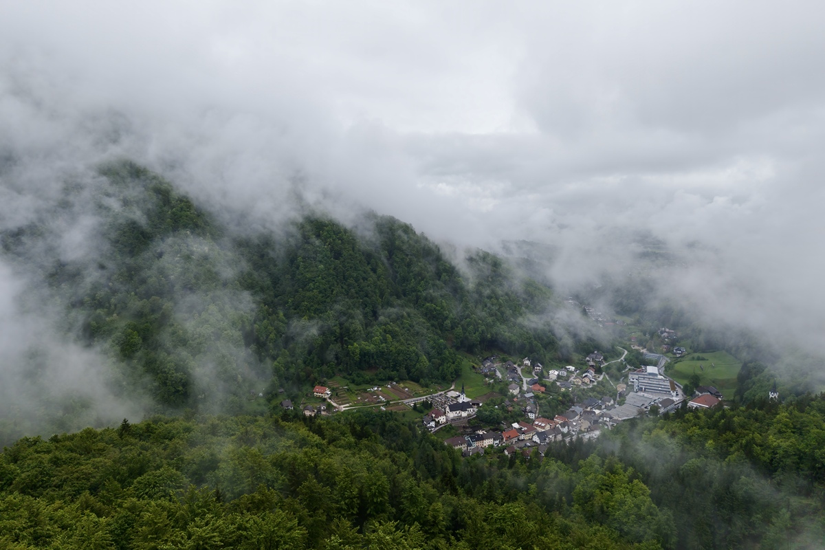 请用100字形容一下房子后远山云雾环绕的场景