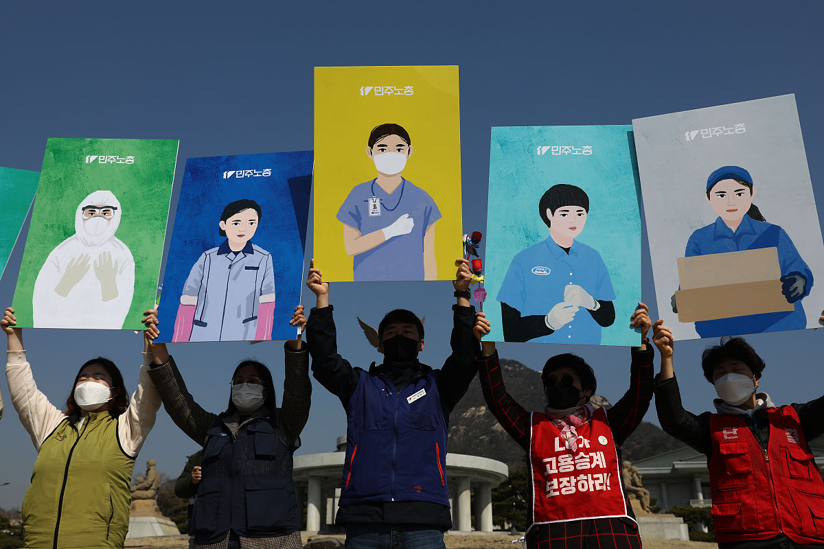 当地时间2021年3月8日,韩国首尔,民众在街头举起牌子与抗议标语,反对