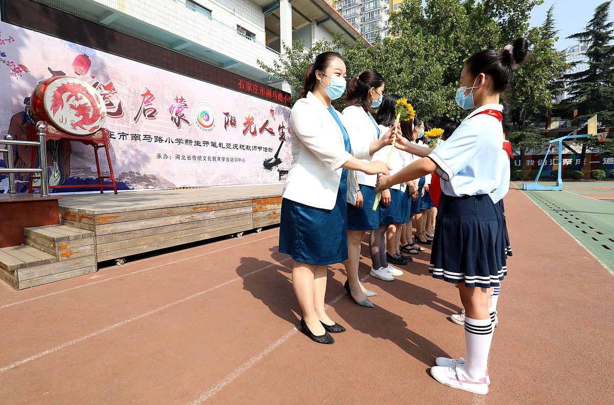 2021年9月9日,在石家庄市南马路小学,少先队员为老师送上向日葵花,感