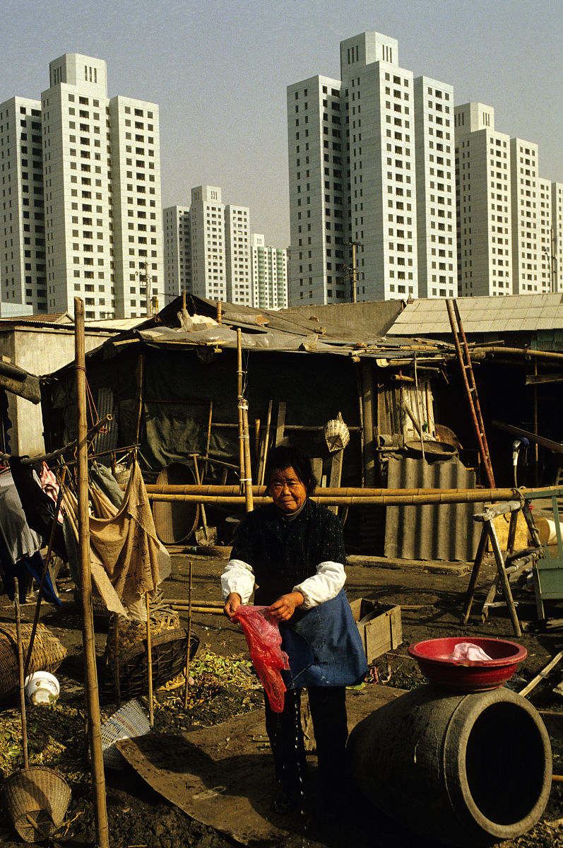 1994年,上海,新的公寓楼和棚屋,一个女人正在棚屋前洗东西.new apartm