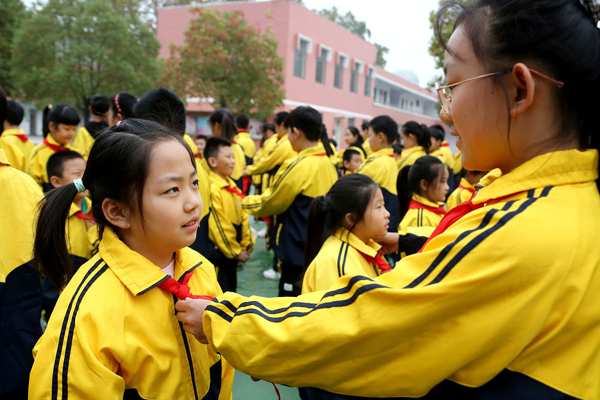 2020年10月12日,山东枣庄,光明路小学学生在给新入队的少先队员佩戴红