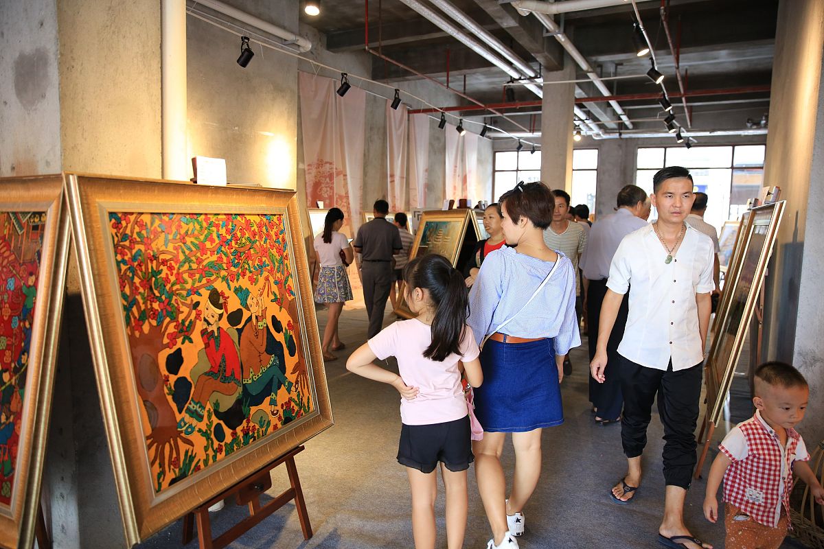 2017年10月1日,在广西柳州市窑埠古镇,游人在观看三江侗族农民漆画展.