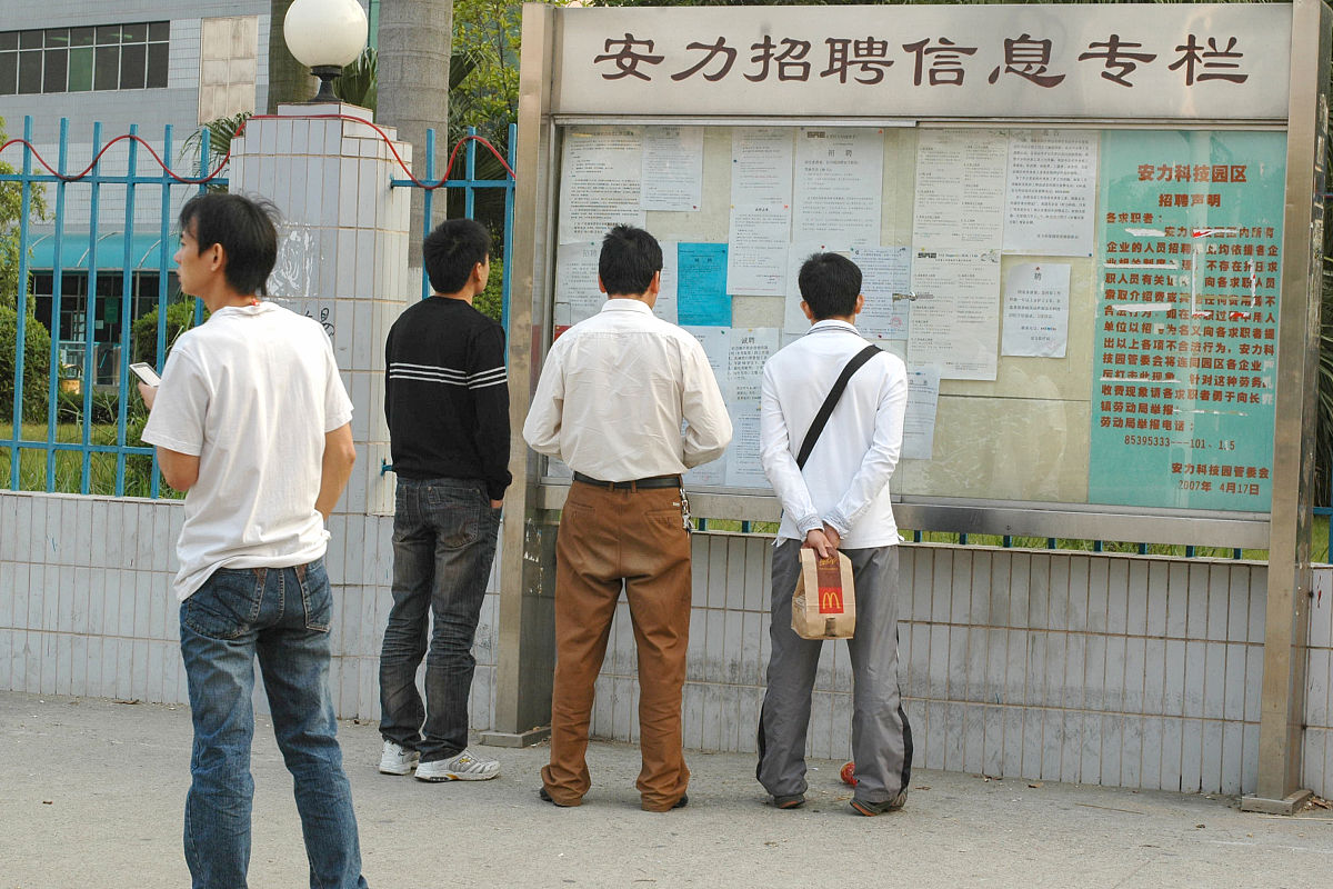 2009年11月28日,广东省东莞市,工业区的打工者查看招工广告.