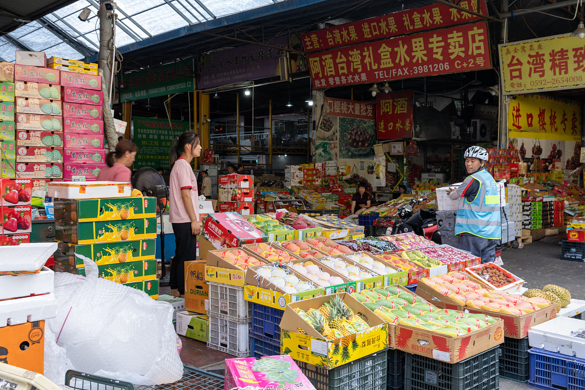 2021年5月15日,福建厦门,中埔水果批发市场,图为顺丰快递员在水果摊收