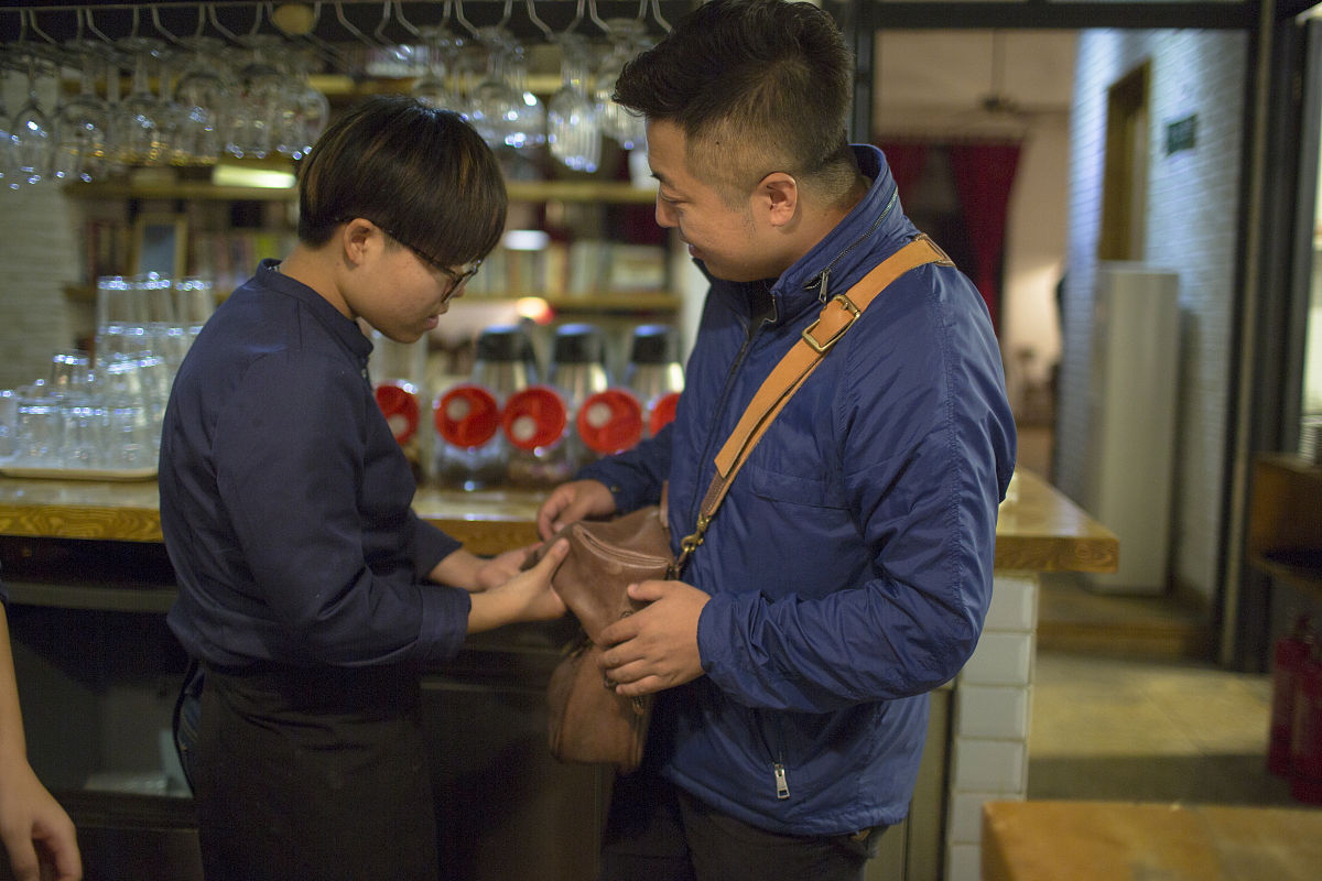 2015年10月22日,西安,咖啡店老板看上小东身上背的包,就背上试一试,很