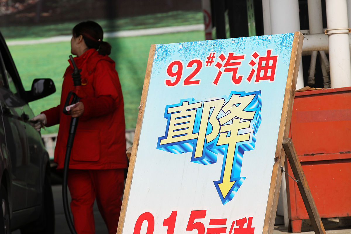 2015年3月24日,江苏南通,加油站工作人员在降价牌子旁为车辆加油.