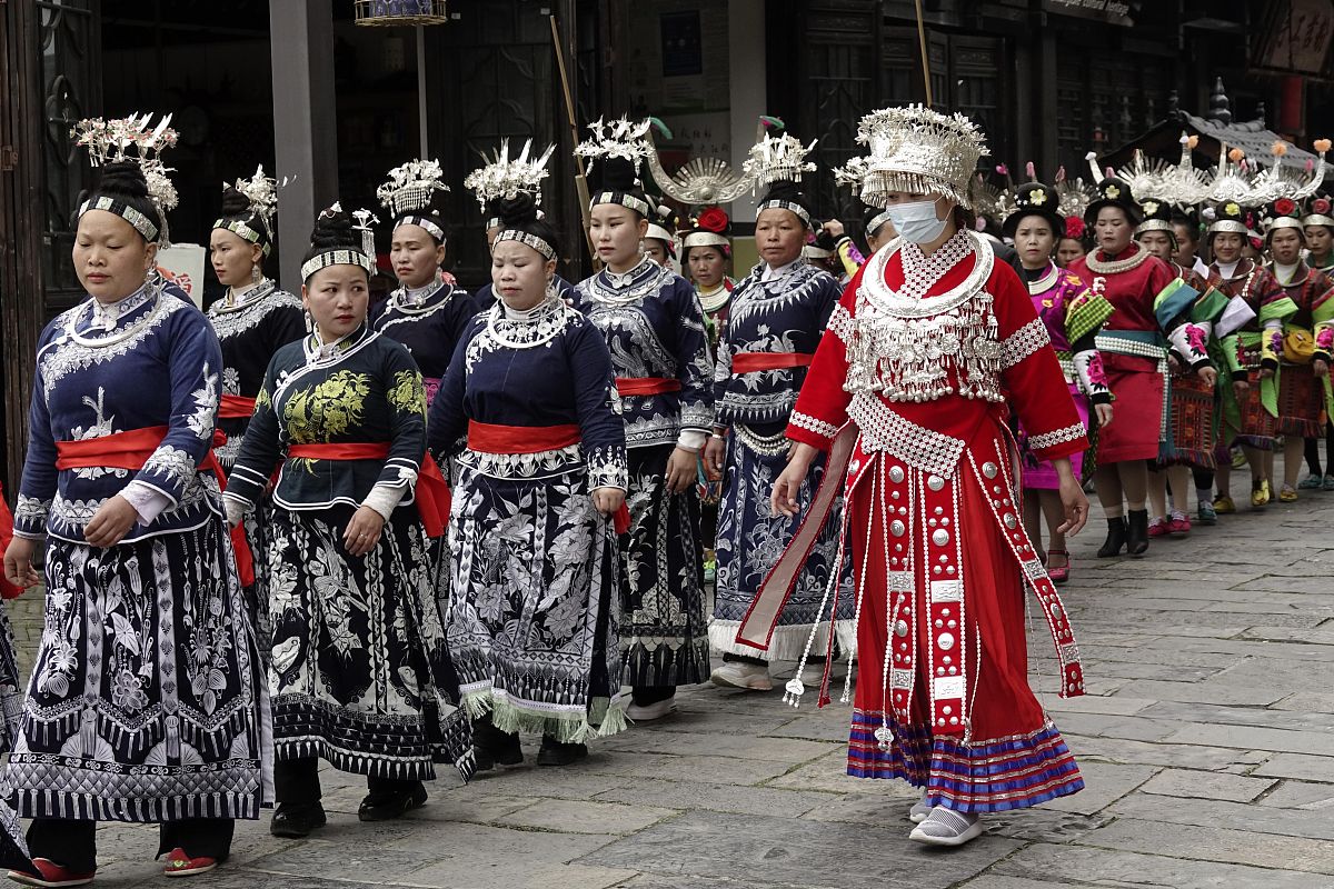2020年4月25日,贵州黔东南,苗族妇女身着节日盛装在万达小镇街道上载