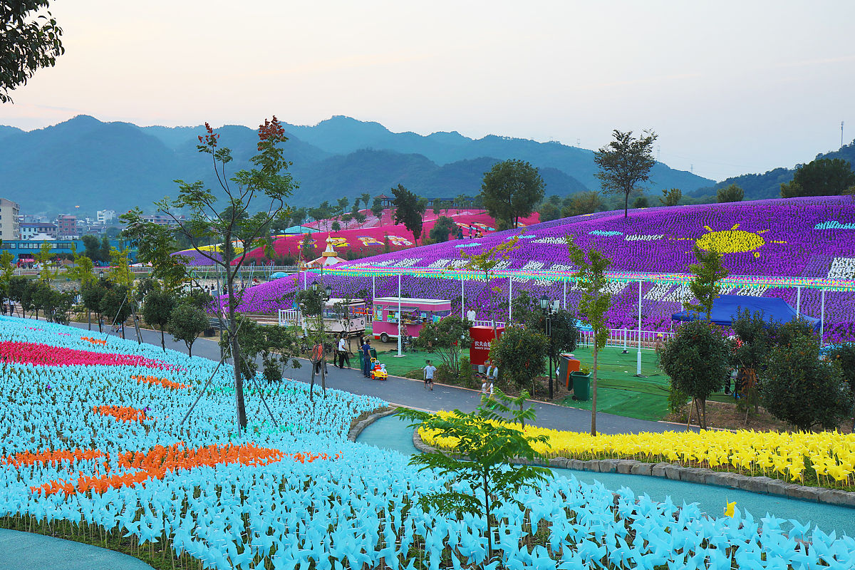 帮我优化一下：这里是花舞人间一个全年都能看花的地方景区有东西两个大门可以乘坐观光车也可以徒步观赏花卉博览园是花舞人间的重头戏景观精致花团锦簇花朵争相斗艳美不胜收一步一景每个点位都能拍出美美的照片赏完花还可以感受一下高空玻璃桥玩累了还可以在湖边休息要是带了小朋友还有专门的沙滩游乐场景区很大项目众多赶快带上家人朋友来呼吸新鲜空气吧。