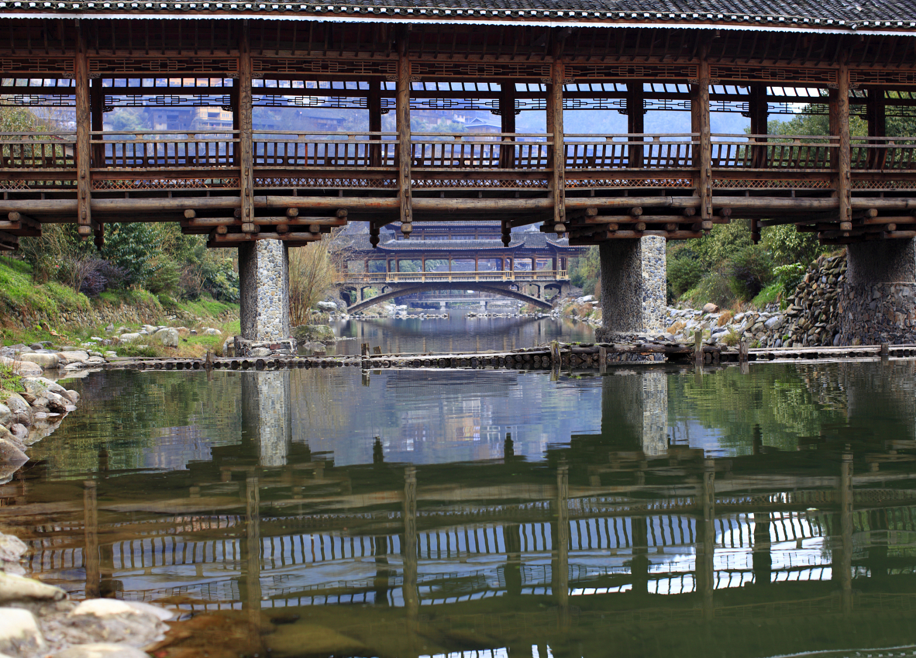 石柱旅游,石柱县城的旗山风雨廊桥是一座独具特色的吊桥,横跨在龙河