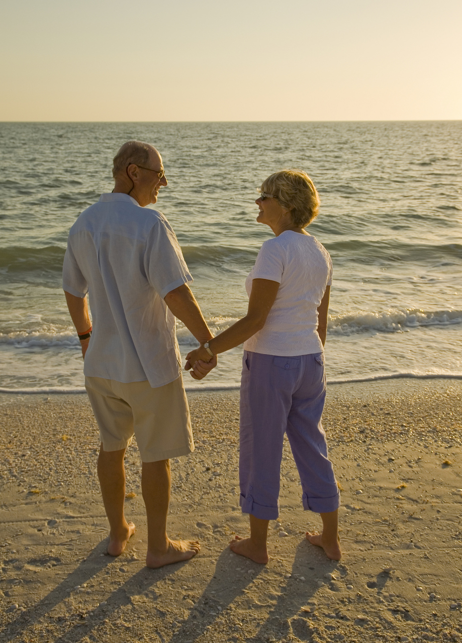 有一对老年夫妻正在散步,太阳下山了,天色渐暗,但他们手牵手仍然很
