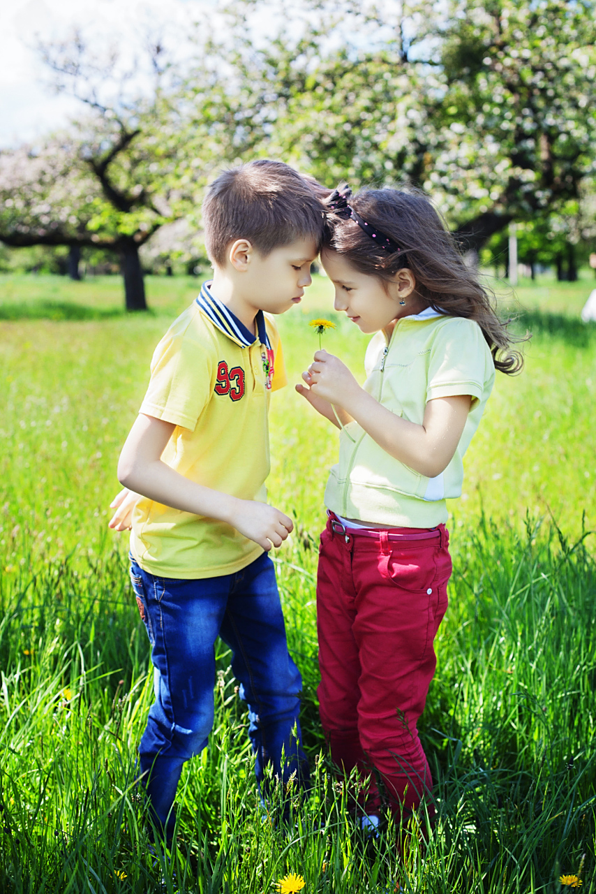 一个小男孩和一个小女孩在公园里玩耍,男孩问女孩:"你会不会爱我?