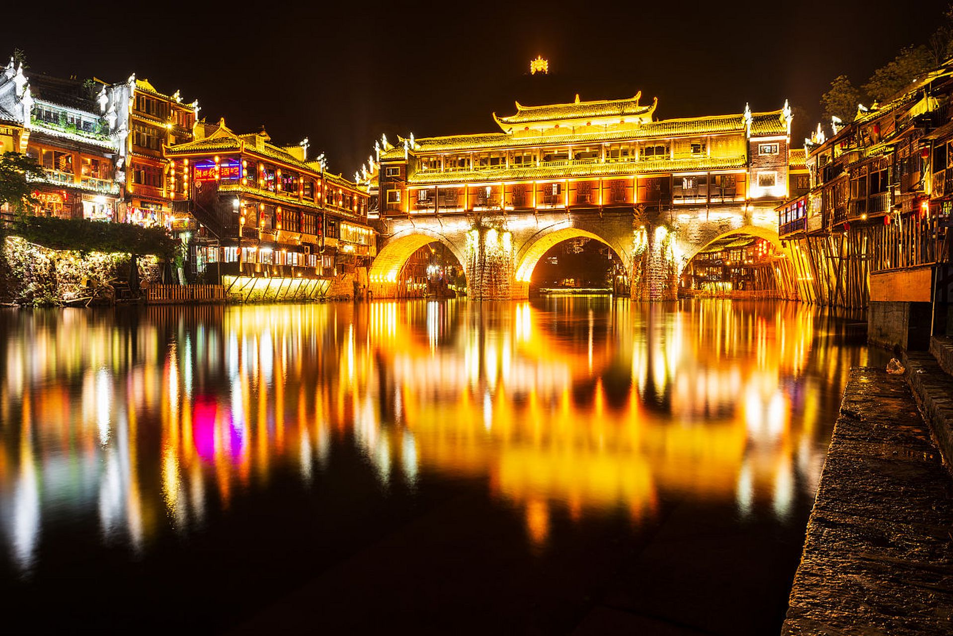 凤凰古城,这座拥有千年历史的古城,在夜晚被灯光照亮,展现出一种别样